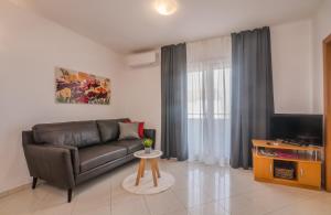 a living room with a leather couch and a television at Apartments Kvarner in Malinska