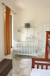 Dieses weiße Zimmer verfügt über ein Kinderbett und ein Fenster. in der Unterkunft Central Oasis Private Pool BBQ in Belmopan