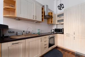 a kitchen with wooden cabinets and a sink at Powstańców Śląskich Homely Apartment in Wrocław