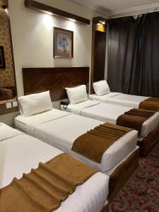 Sky View Hotel, Madinah في المدينة المنورة: غرفة فندقية بأربعة أسرة مع بطانيات بنية اللون
