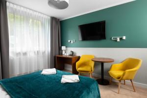 シュチトナにあるDom Wczasowy KAMELAのベッド1台と黄色い椅子2脚が備わるホテルルームです。