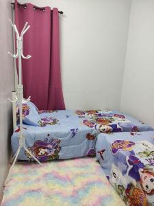 a bedroom with two beds and a pink curtain at Maileyna Homestay 1.0 in Alor Setar