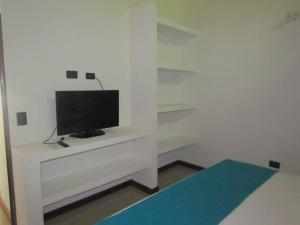 Una habitación con un televisor sobre un escritorio blanco. en Cabañas La Española, en Coveñas