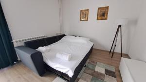 1 dormitorio con 1 cama con sábanas blancas y toallas en Vera City Square Apartment, en Skopje