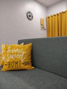 a yellow pillow on a couch with a home sweet home sign at Maileyna Homestay 1.0 in Alor Setar