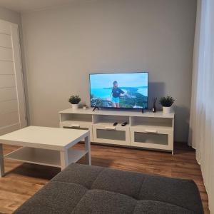 ein Wohnzimmer mit einem Flachbild-TV auf einem weißen Schrank in der Unterkunft Butas Sedos gatvėje in Telšiai