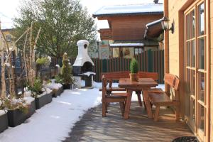 une terrasse avec une table et des bancs dans la neige dans l'établissement Alpen Chalets Zell am See, à Niedernsill