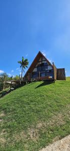 ein Haus auf einem grasbewachsenen Hügel mit einer Palme in der Unterkunft Mirante das Cabanas in Guarapari