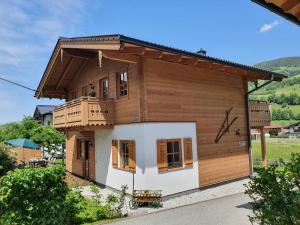 Alpen Chalets Zell am See في نيدرمسيل: منزل خشبي صغير مع شرفة عليه
