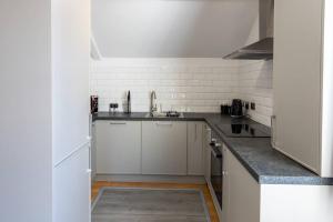 una cocina con armarios blancos y fregadero en 2BR Dorset Charming Apartment in Towncenter, en Christchurch