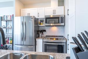 a kitchen with a stainless steel refrigerator and microwave at Toronto Views ~ Pool ~ BBQ ~ Harbourfront ~ WIFI in Toronto