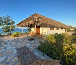 une cabane avec banc et toit de chaume dans l'établissement Namahamade Lodge Restaurante & Beach Bar, à Mossuril