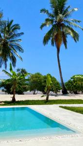 una piscina con palmeras en una playa en Lions Villa Zanzibar with private pool - LUXURY ON THE SEASIDE en Kiwengwa