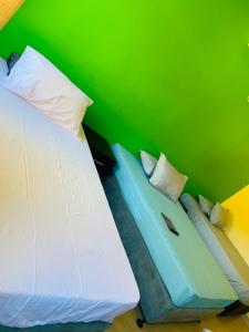 1 dormitorio con cama blanca y pared verde en Ká Jackson Bilene, en Vila Praia Do Bilene