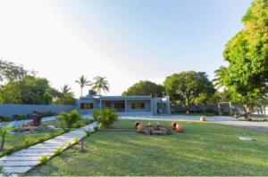 a house with a grass yard with a building at Ká Jackson Bilene in Vila Praia Do Bilene