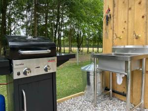 a grill and a sink next to a table at Woodland Glamping Retreat in Toppesfield