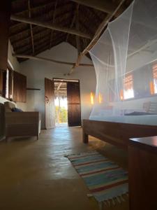 Namahamade Lodge Restaurante & Beach Bar في Mossuril: غرفة نوم بسرير واريكة في غرفة