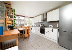 una cocina con armarios blancos y una mesa. en chic 3-BR home welll located in Islington en Londres