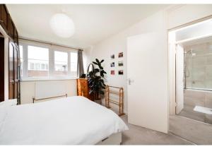 Habitación blanca con cama y ventana en chic 3-BR home welll located in Islington en Londres