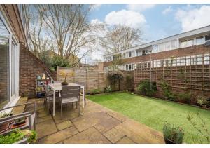a small backyard with a table and a lawn at chic 3-BR home welll located in Islington in London