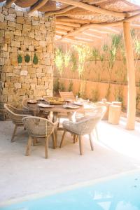 eine Terrasse mit einem Tisch, Stühlen und einer Steinmauer in der Unterkunft Na Xamena in La Croix-Valmer