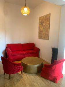 - un salon avec un canapé rouge et deux chaises dans l'établissement Le Beaufleury et sa terrasse à la Victoire, à Bordeaux