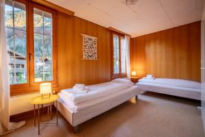 a room with two beds and two windows at Chalet Seehus Iseltwald in Iseltwald