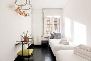 a white room with two beds and a window at Eulalias Lodges Barcelona in Barcelona