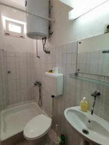 ein Badezimmer mit einem WC, einem Waschbecken und einer Badewanne in der Unterkunft Apartmani Slaviček in Živogošće