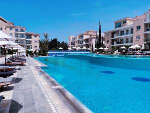 a large blue swimming pool with chairs and umbrellas at Elysia Park in Paphos