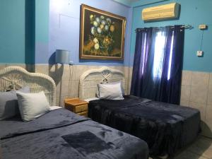 Habitación con 2 camas y una pintura en la pared. en Caribbean Tourist Villa en Puerto España