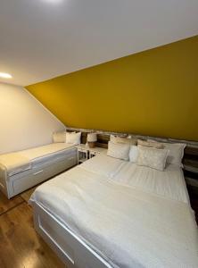 2 Betten in einem Zimmer mit gelber Wand in der Unterkunft Casa Rustik Nyaraló in Praid