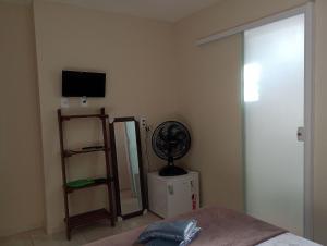 een slaapkamer met een bed, een ventilator en een spiegel bij HoStel de Setiba - HOSPEDARIA OCA RUCA in Guarapari