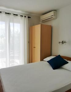 a bedroom with a white bed and a cabinet and a window at Apartmani Slaviček in Živogošće