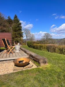 a wooden deck with a fire pit in the grass at Stoneymollan over Loch Lomond in Balloch