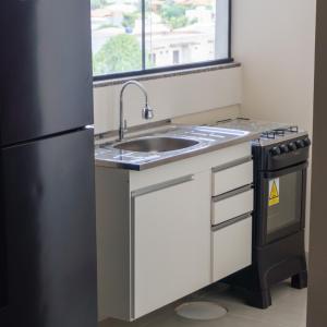 uma cozinha com um lavatório e um frigorífico em De Paula Apart Hotel em Espigão dʼOeste