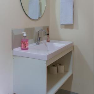 uma casa de banho com um lavatório branco e um espelho. em De Paula Apart Hotel em Espigão dʼOeste