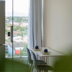 uma mesa e duas cadeiras em frente a uma janela em De Paula Apart Hotel em Espigão dʼOeste
