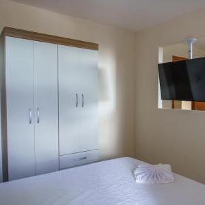 um quarto com um armário branco e uma cama em De Paula Apart Hotel em Espigão dʼOeste