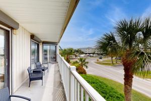 a balcony with chairs and a palm tree on a house at Bay Creek Villa - 202 in Edisto Beach