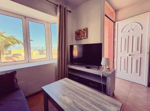 uma sala de estar com uma televisão, uma mesa e janelas em Casa Noble em Costa de Antigua