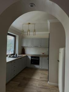 a kitchen with white cabinets and an archway at Paltin Evergreen Garana in Gărâna