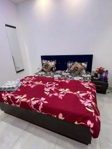 a bed with a red blanket and pillows on it at Estates Model in Greater Noida