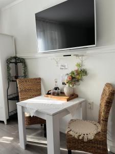 a white table with two chairs and a tv on a wall at Rooms Zana in Split