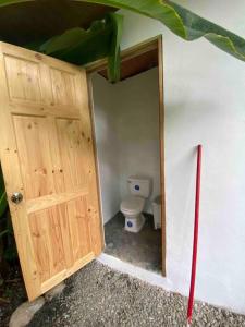 ein Badezimmer mit einer Holztür und einem WC in der Unterkunft Jungle Bungalow with Small Pool in Talamanca