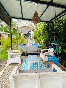 eine Terrasse mit Stühlen, einem Tisch und einer Schaukel in der Unterkunft Jungle Bungalow with Small Pool in Talamanca