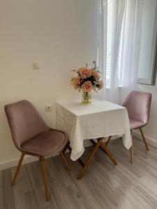 a vase of flowers on a table with two chairs at Rooms Zana in Split