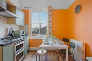 una cocina con paredes de color naranja y una mesa y sillas blancas. en Harbour Court - Free Parking - tucked away on the Barbican - by Ocean City Retreats en Plymouth