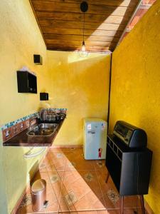 una pequeña cocina con fregadero y nevera. en Rancho Ubuntu en Brumadinho
