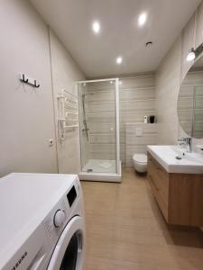 a washing machine in a bathroom with a shower at Tarp Pušų - Jaukūs apartamentai - 15 min iki jūros in Palanga